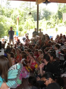 Photo of a large group of children watching the puppet show, some wearing butterfly wings