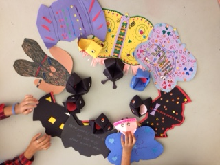 Colorful paper puppet bats and butterflies made of construction paper and decorated with stickers, markers, and more paper.