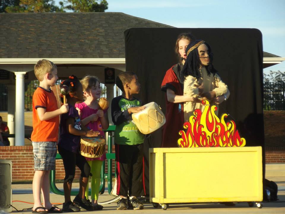 children with instruments on stage with the puppeteer and Chief Gray Eagle puppet