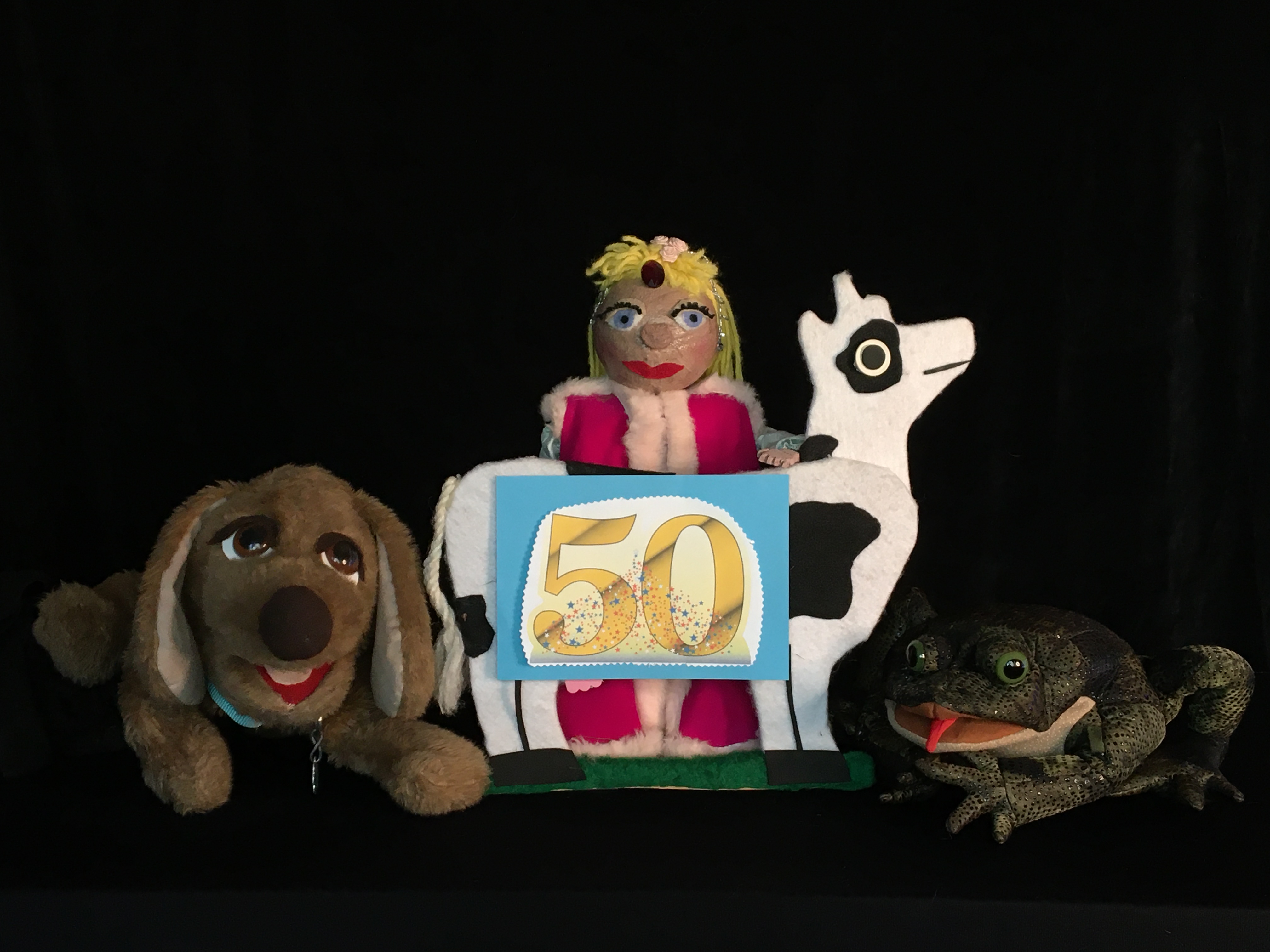 Dog, princess, cow and frog puppets holding a golden 50 sign